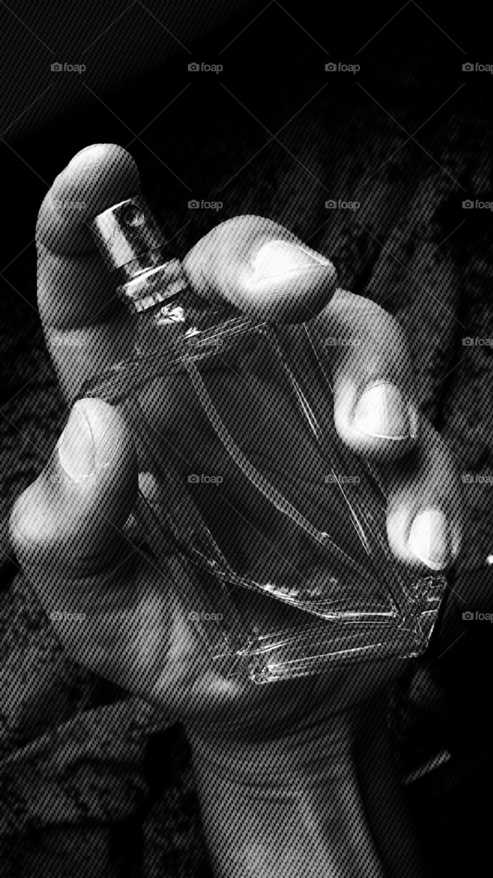 Em preto e branco imagem; mão com perfume. Frasco com transferência.