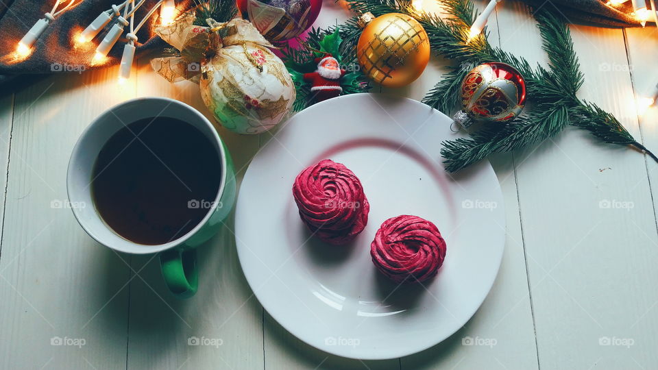 Christmas toys, a cup of hot tea, marshmallows and Christmas decorations on a white table