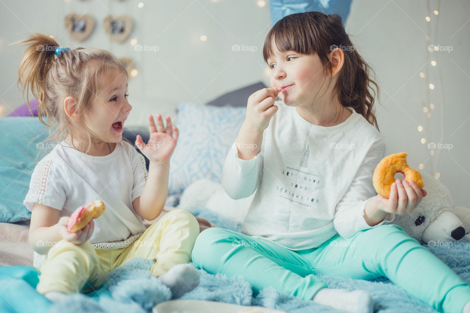 Little sisters eating the donuts