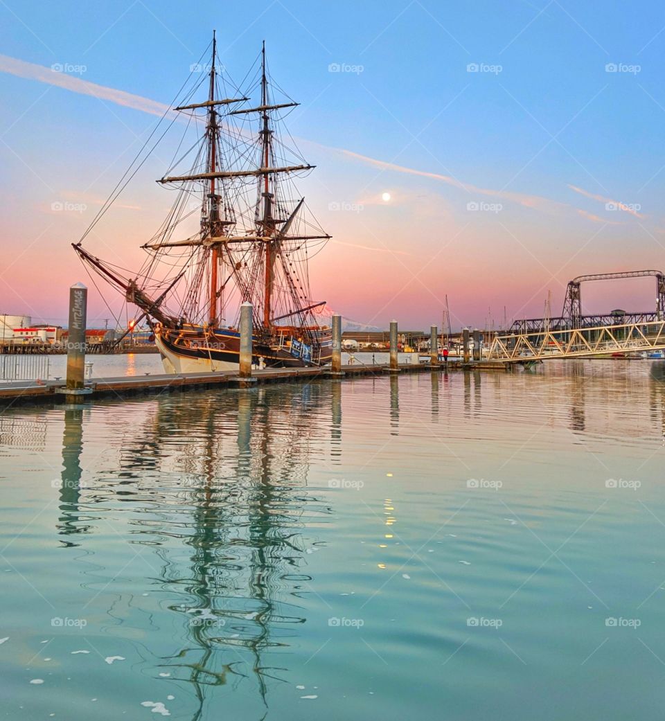 tall and vintage ship with full moon rising in a beautiful and colorful setting