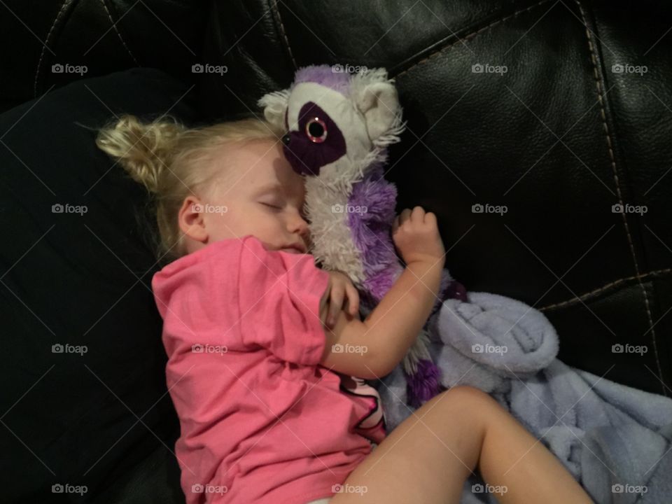 Little girl sleeping on the couch with her toy