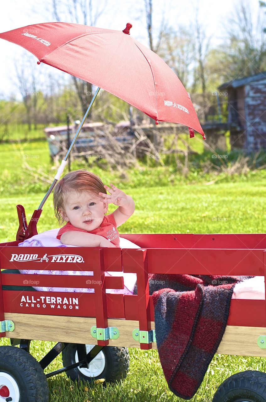 Little red wagon. Little girl riding in her wagon
