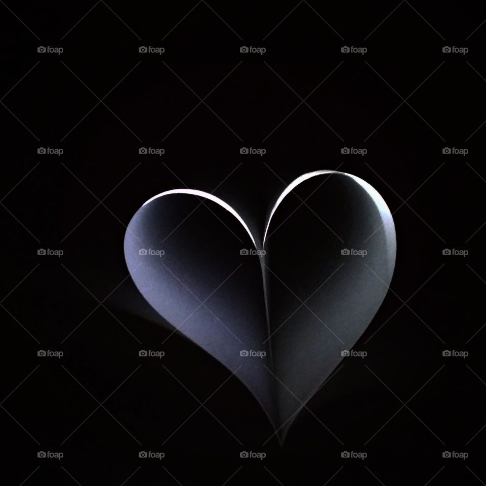 Books in the dark look glowing in the shape of a heart.