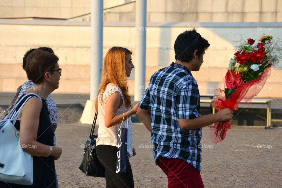People walking on street with bouquet in hand