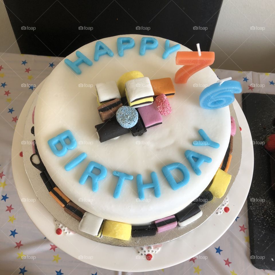 Birthday cake with candles and blue birthday message. Sweets candy on top 