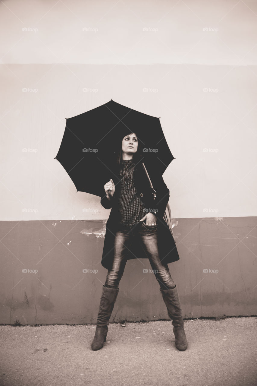 Stylish young woman standing with umbrella