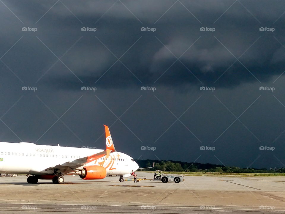 Foto de um avião da gol, tirada da pista do aeroporto de Guarulhos, ao fundo o seu fechado, minutos antes de uma tempestade