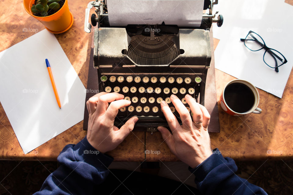 A young writer is writing a new book on an old typewriter.