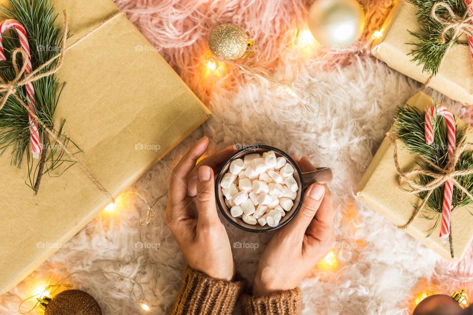 Flat lay of woman holding hands cup of cocoa with marshmallow 