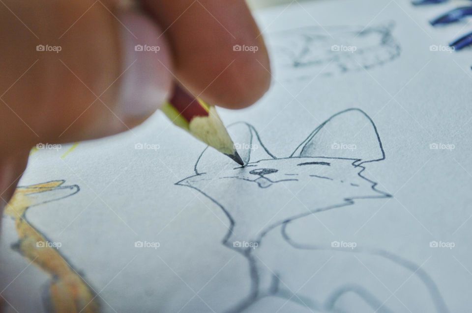 I relax when I draw. in the photo my hand with a pencil and a drawn cat on paper