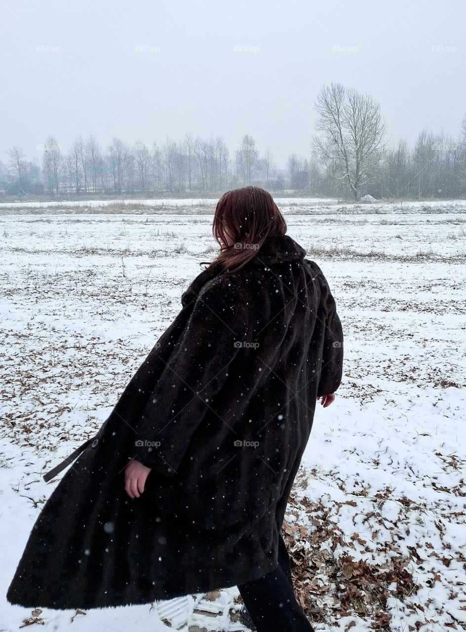 photo moment of a young girl from a winter walk in a fur coat in the middle of a wild field