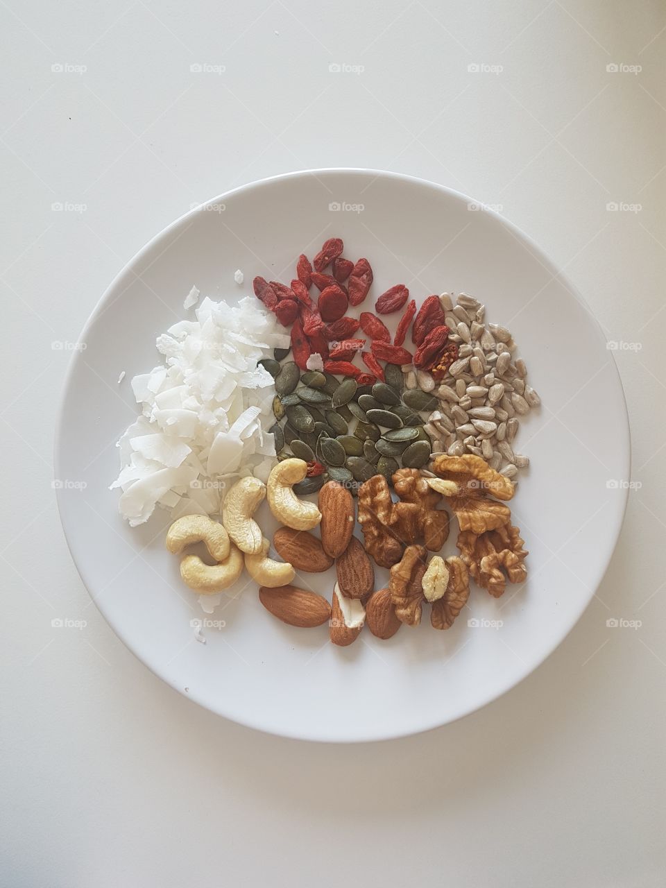 Healthy colorful snack with seads and nuts combined in a white dish.