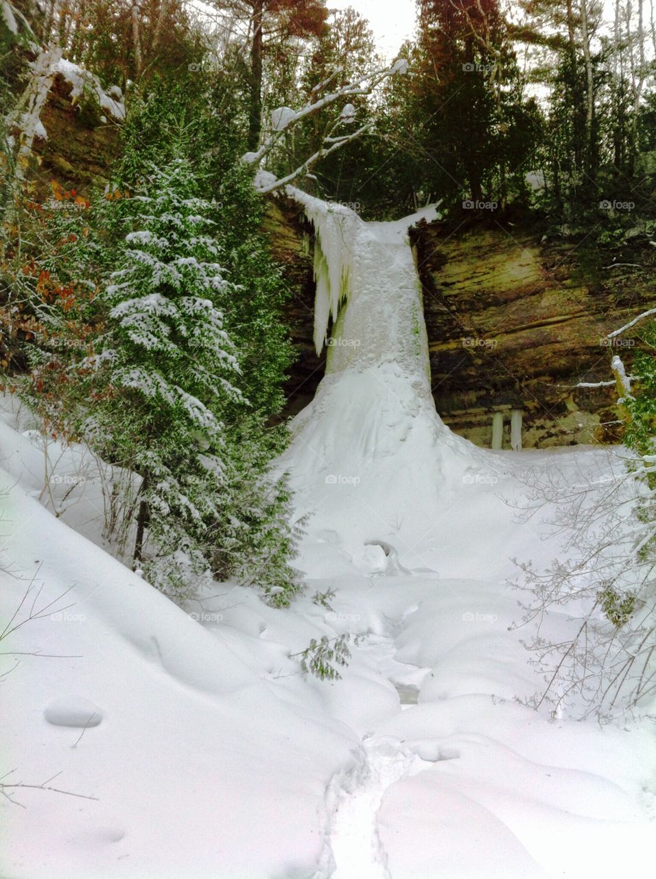 Frozen waterfall on a hike through a trail in the woods in northern Michigan