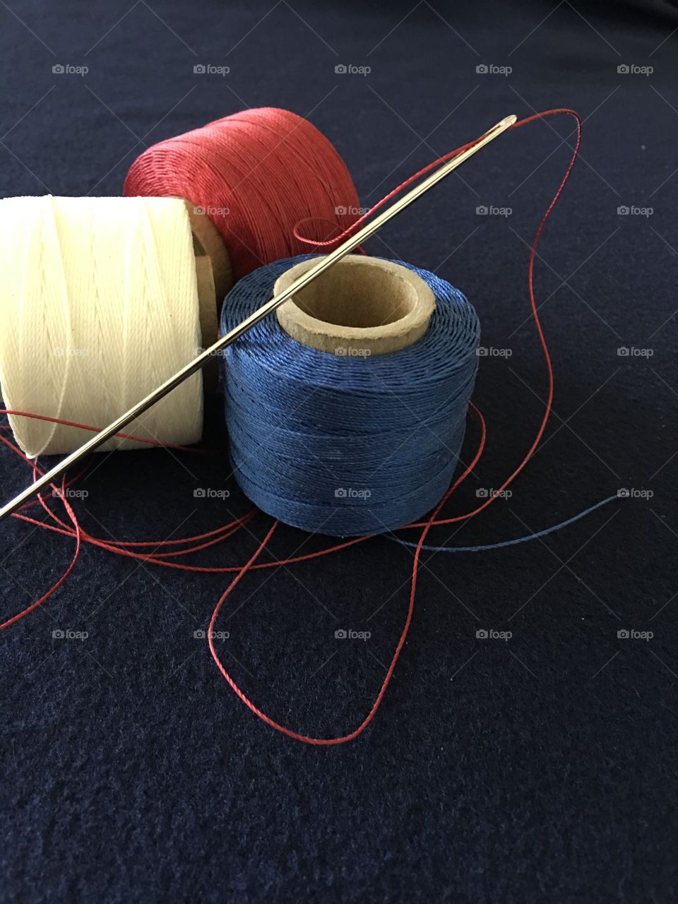 Red white and blue bolts of thread with needle 