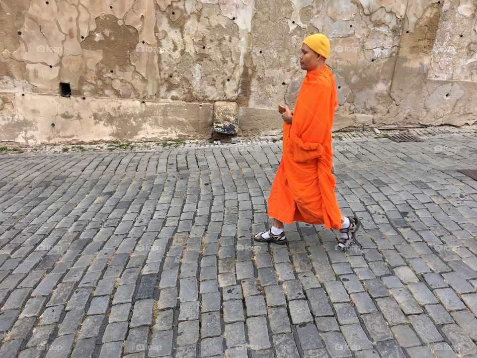 Prague ... Buddhist monk wearing a colourful orange robe and a yellow hat 