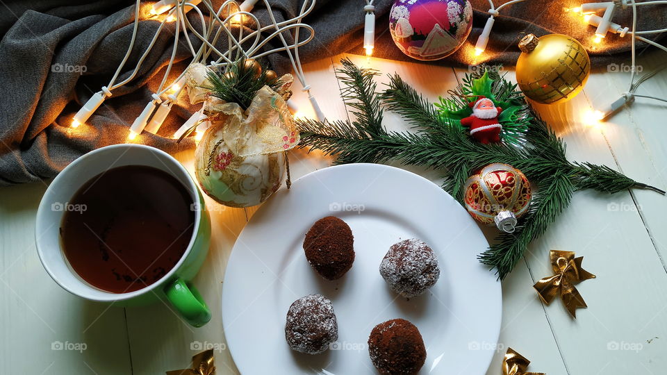 Christmas toys, a cup of hot tea, delicious Christmas garland cake on a white table