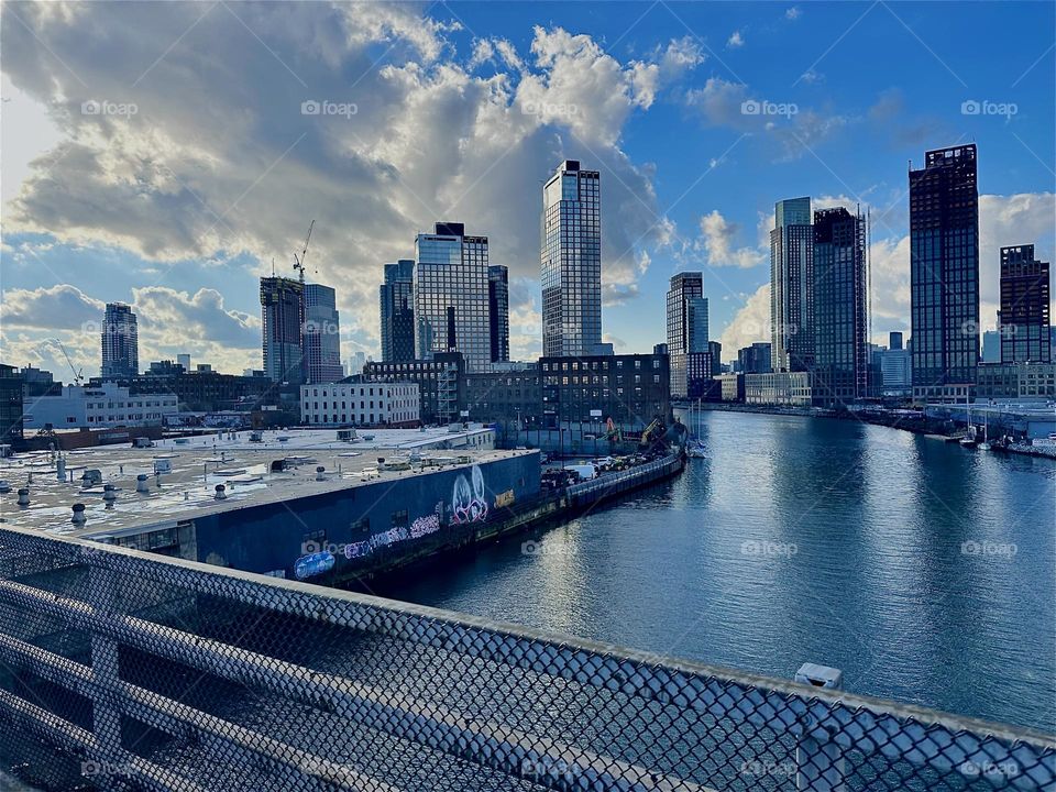 This is “Newtown Creek” seen from the “Pulaski Bridge” that connects LIC, Queens to “Greenpoint”, Bklyn. Across the water of the “East River” we see “Greenpoint” on the left and LIC and “Manhattan” on the right. 2023. Hypnotic Productions