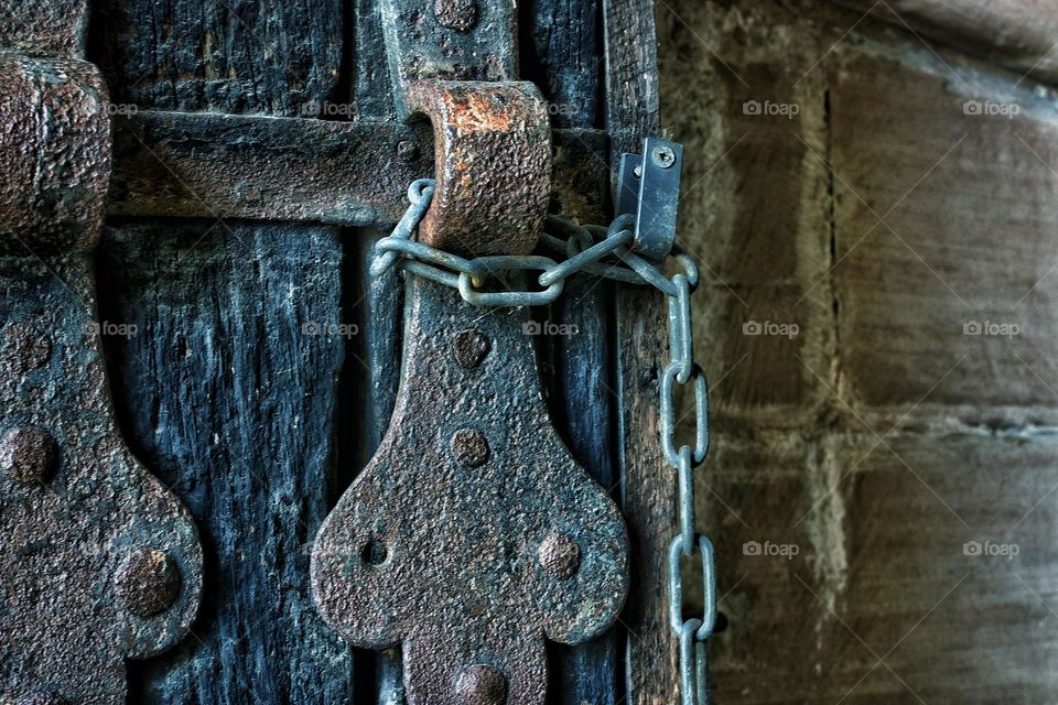 Closeup of an old rusty door lock with chain on a wooden door