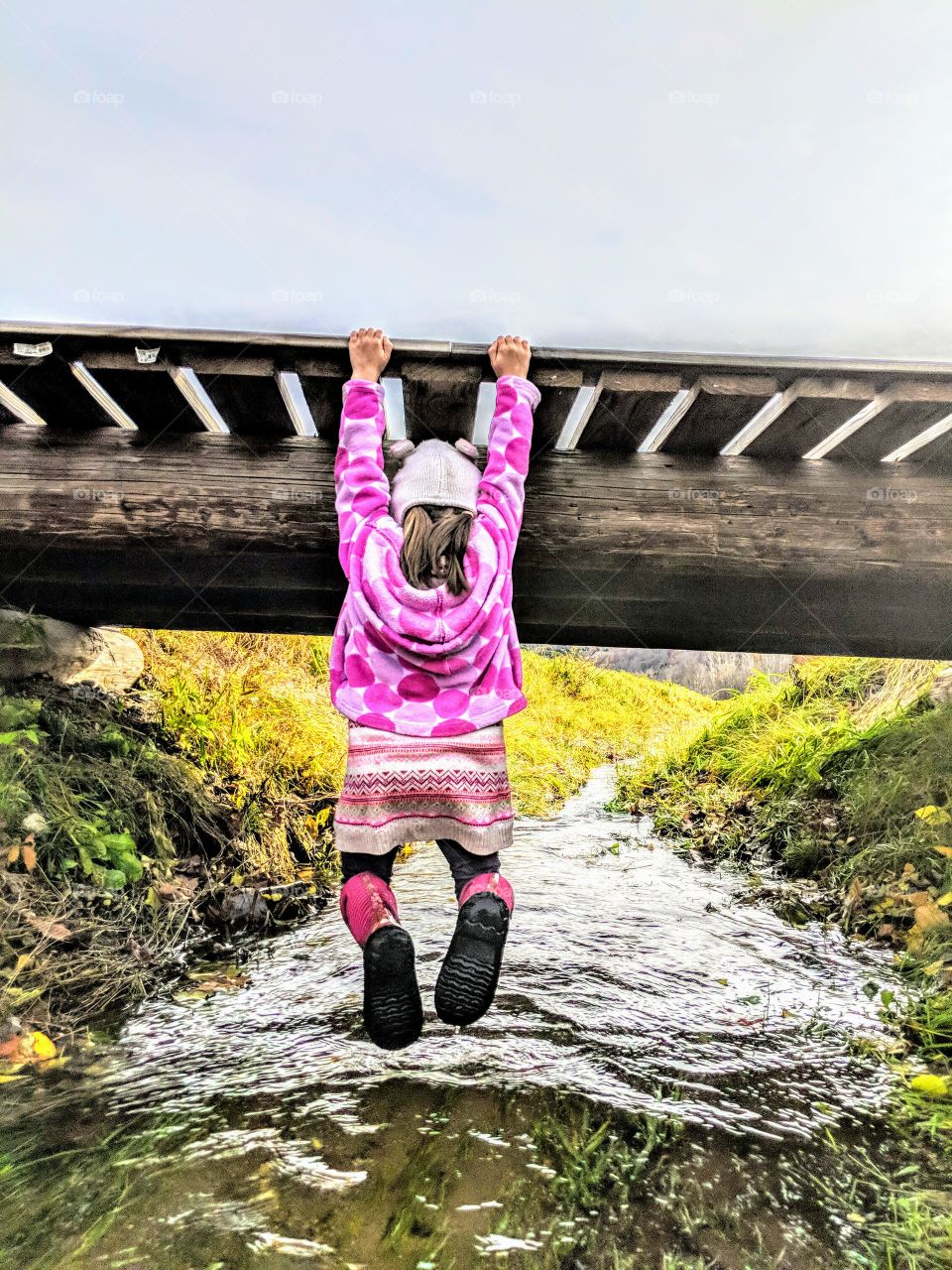 girl holding onto bridge