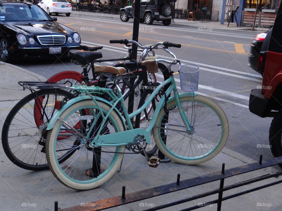 Ultimate Summer Bicycle. Sea foam green beach cruiser parked against pole in Chicago. 