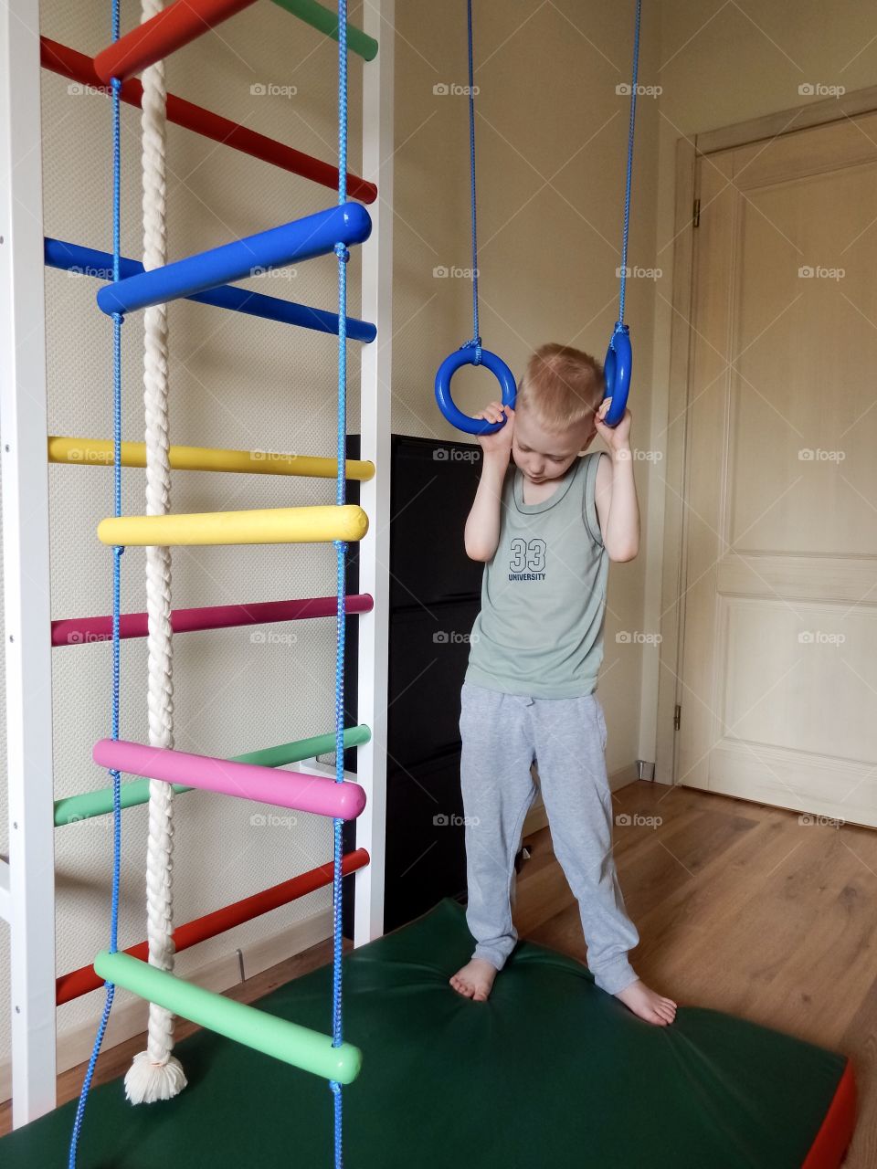 Tired boy goes in for sports on gymnastics rings, home work out