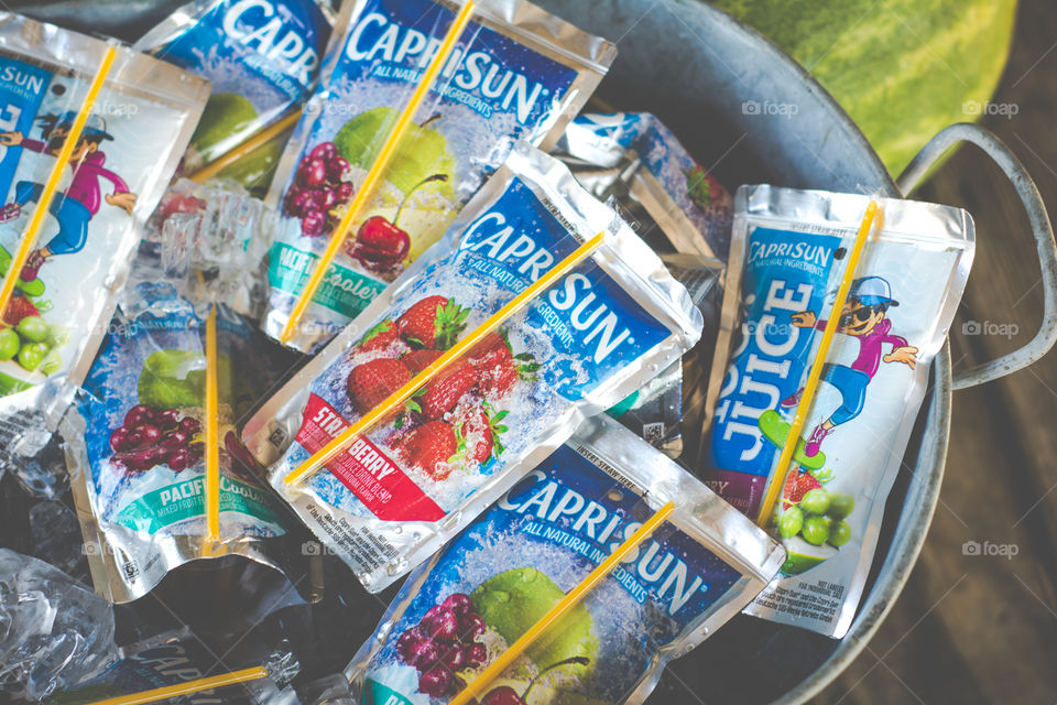 Bucket of Capri Sun Juice Pouches on Ice with Watermelon in Background 