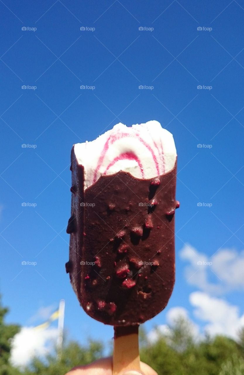holding ice cream against blue sky