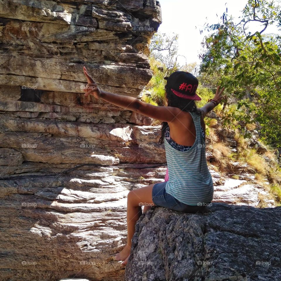 Freedom at the edge of a rock. Girl with stretched arms