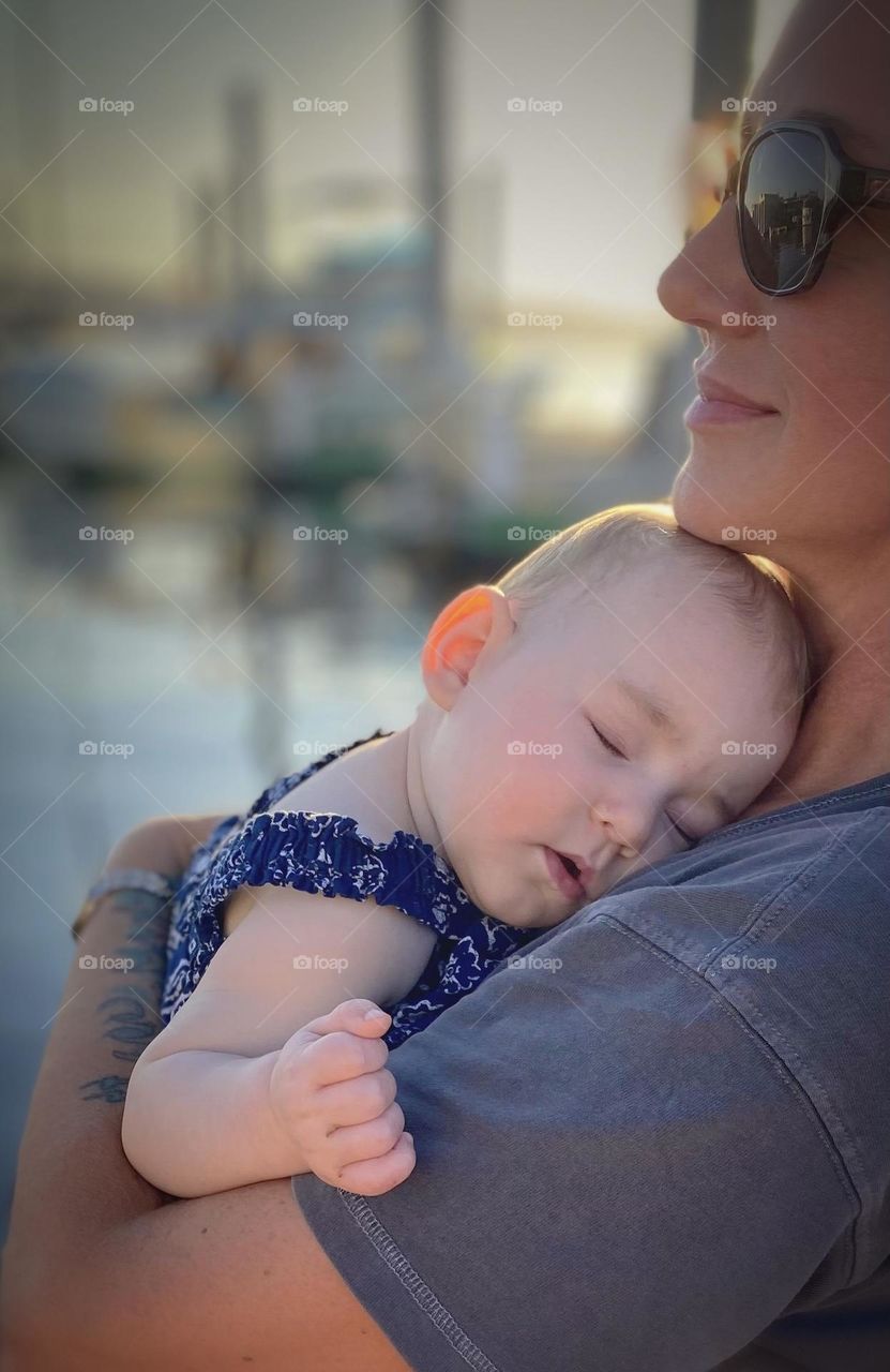 An infant girl takes a much needed nap in the arms of a loving adult while strolling on a warm summer evening