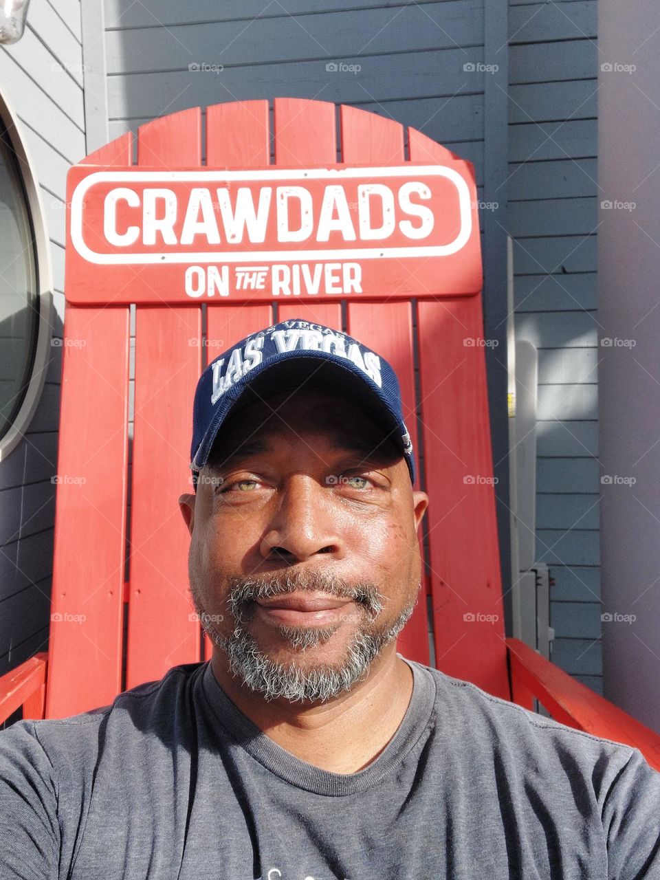 Sitting on a big red chair outside of a restaurant on the riverfront in Sacramento California