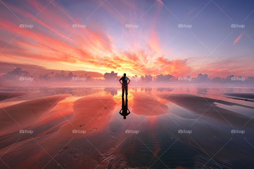 Man alone at seaside beach during sunrise