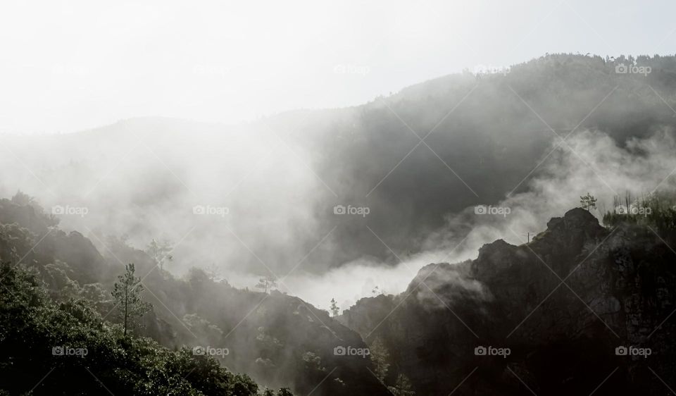 White mist evaporates from ragged mountain ridges early in the morning