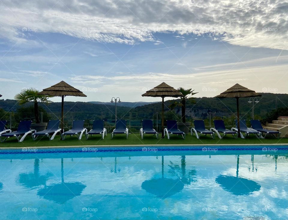 Reflecting clouds and umbrellas in the pool 