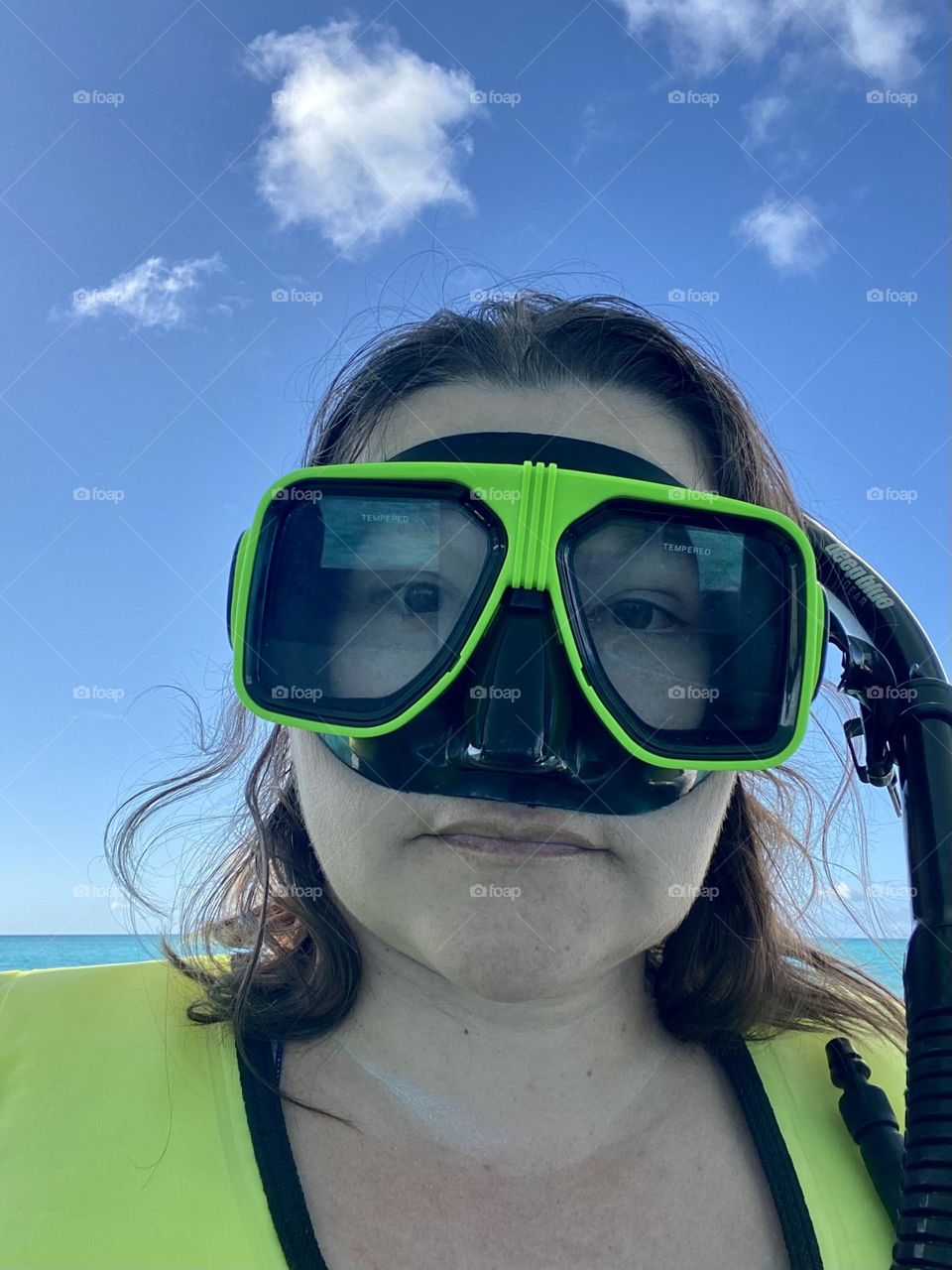 A person wearing a brightly colored snorkel mask and life jacket