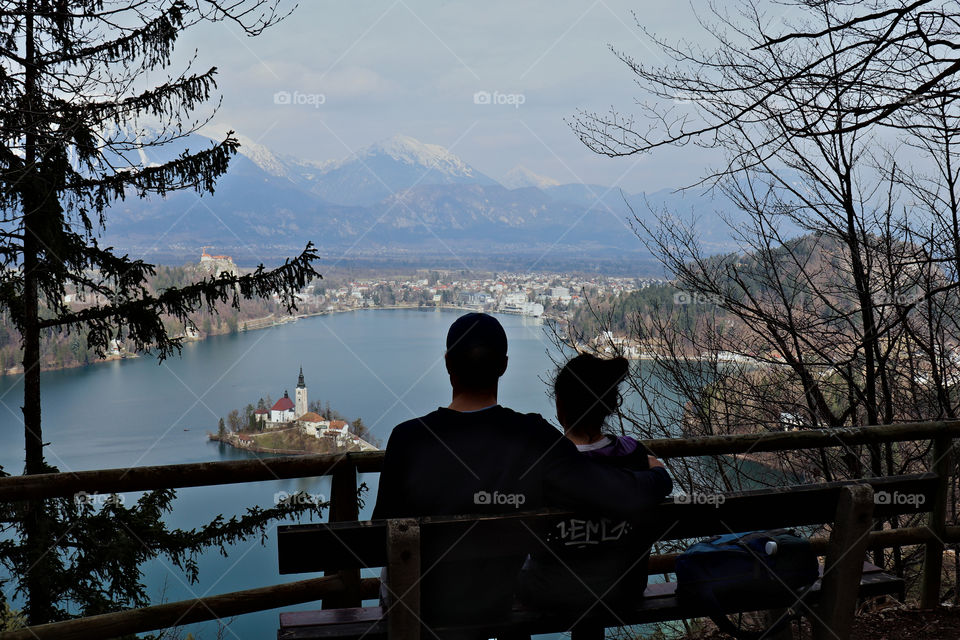 Couple sitting on bench looking at bled island and castle