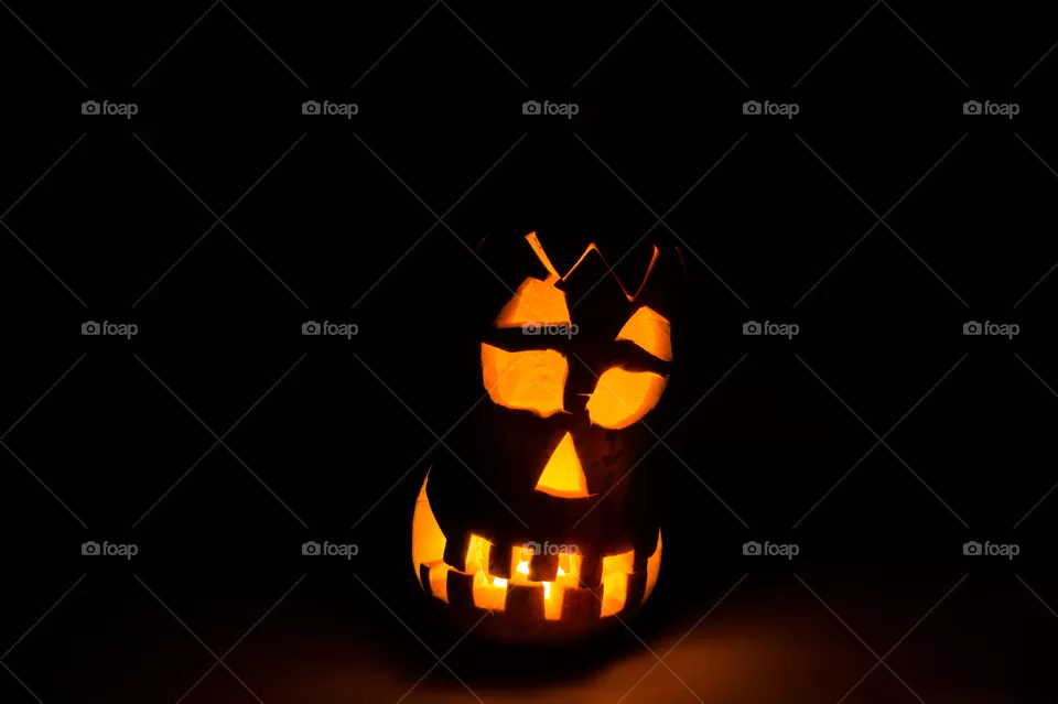 Evil pumpkin face for Halloween in a dark room at night close-up.