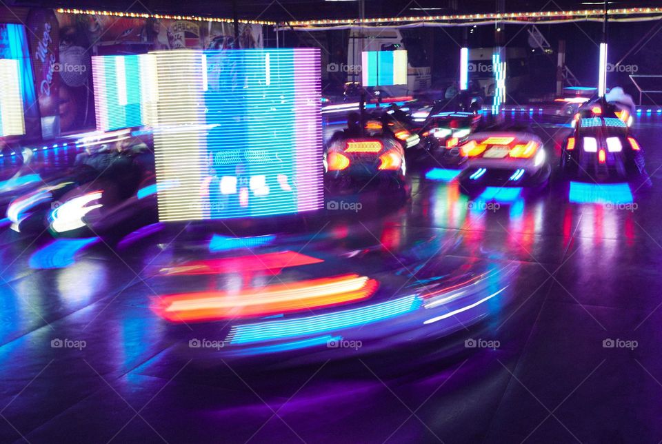 Long exposure photo of neon lights on bumber cars at an amusement park