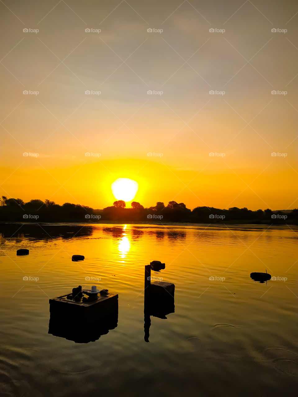 The sun rises along the river with the idol of Lord Shiva inside the river water