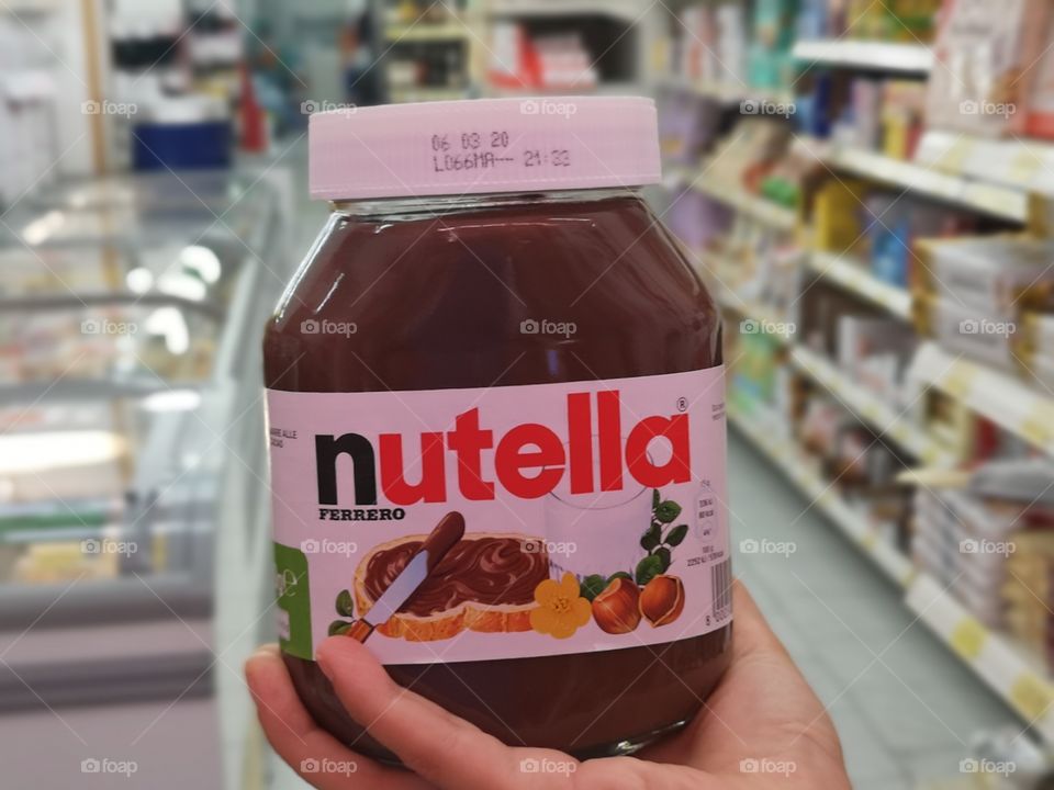 woman holds a can of Nutella in the supermarket aisles