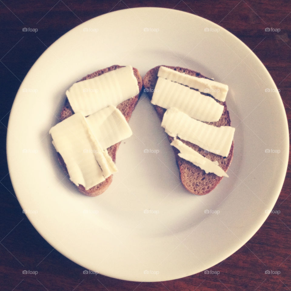 2 slices of black bread and butter on a white plate from above