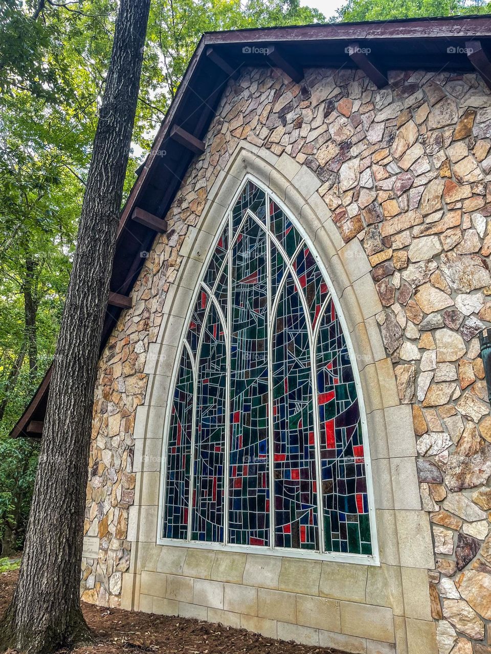 A stained glass mosaic window of an old church can be seen alongside what appears to be a deep green forest