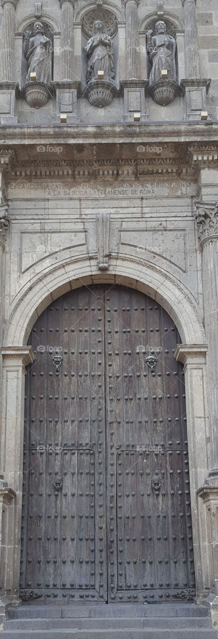 one of the old entrances to the Cathredral Basilica in Gudalajara. Large heavy wooden doors about 15 to 20 feet tall.