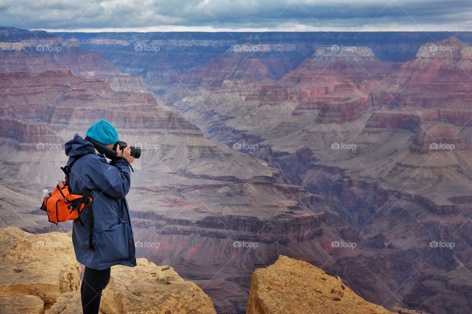 Woman standing on the edge of the Grand Canyon taking photos