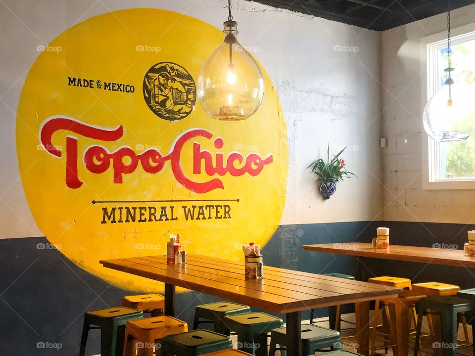 Tables at a Mexican restaurant with a bright yellow wall mural