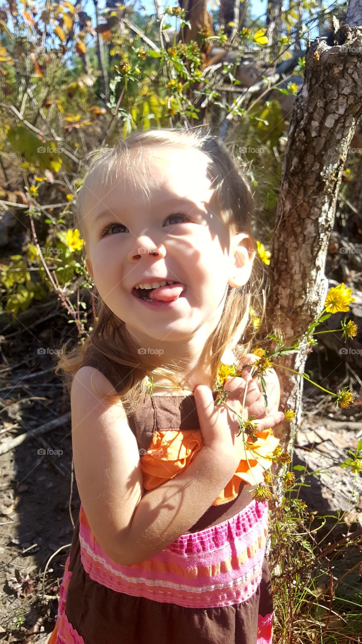 cute girl my daughter smiling with bushes and flowers and trees and shadows and sunshine Vidor Texas United States of America 2017