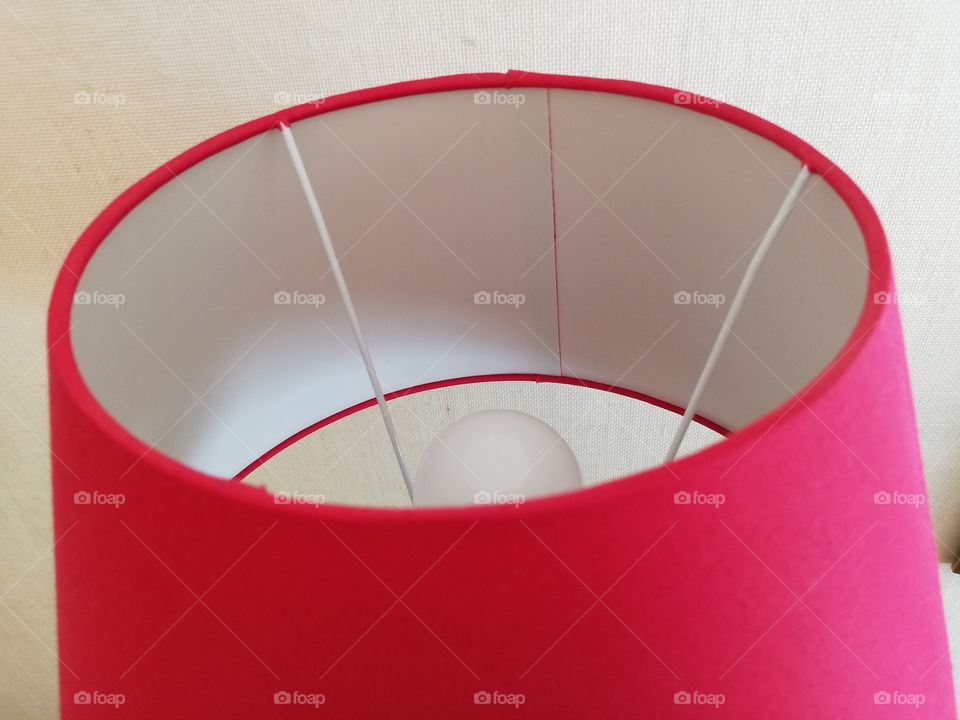 The light is off and the round lamp has a shadow inside the pink lampshade