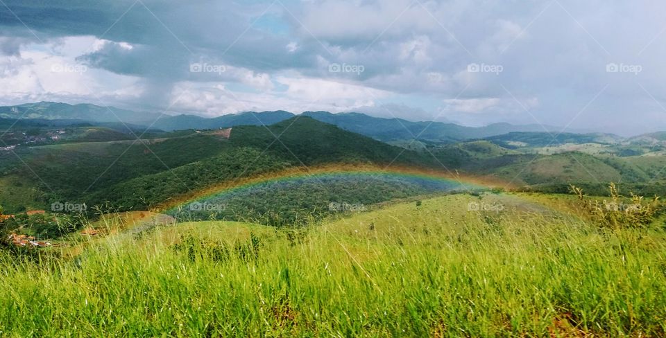 Surprising rainbow on a valley during a car trip.