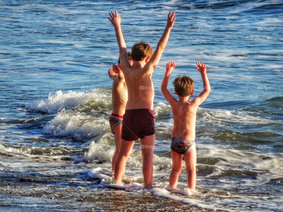 Young Boys Raising Hands To The Sea. Brotherhood
