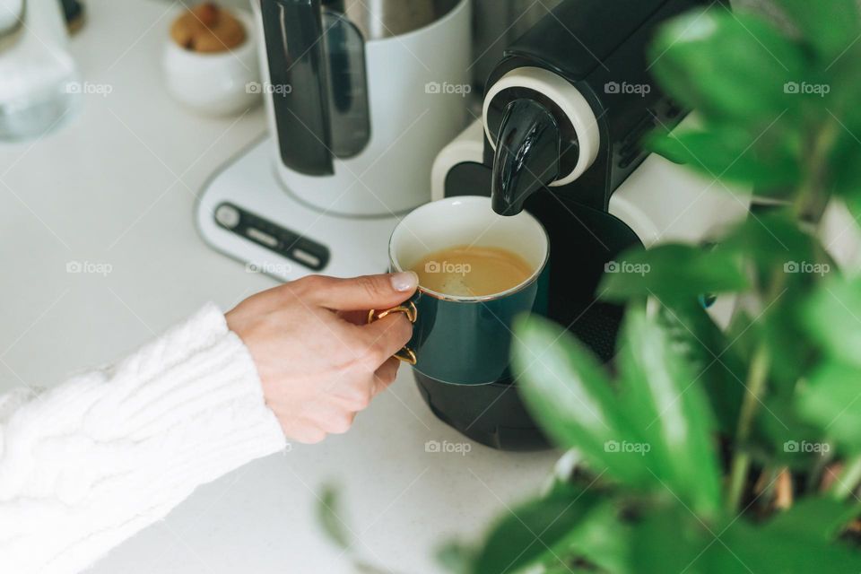 Young woman making coffee from machine at home 