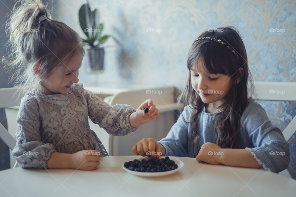 Little sisters with blueberries at home 
